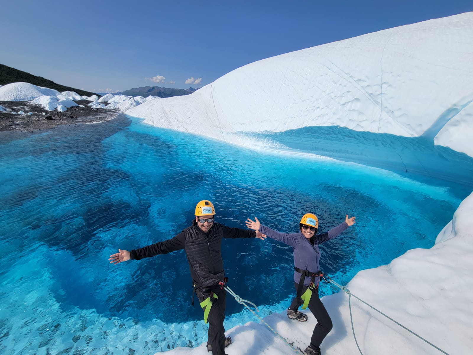 Explorers on ropes over blue glacial lake