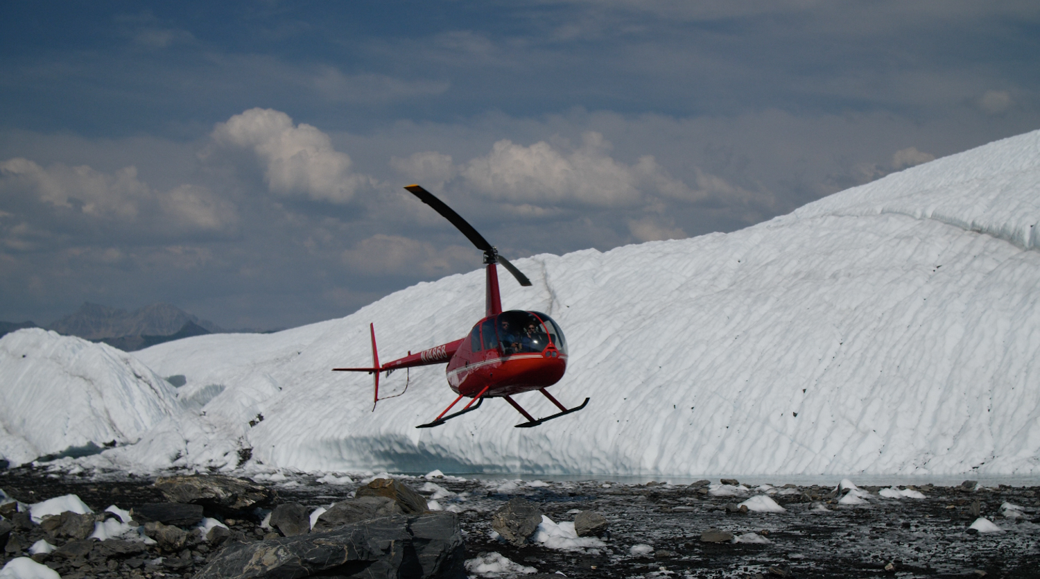 red heli landing on glacier ice and rock