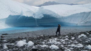 person standing in front of glacier waterfall