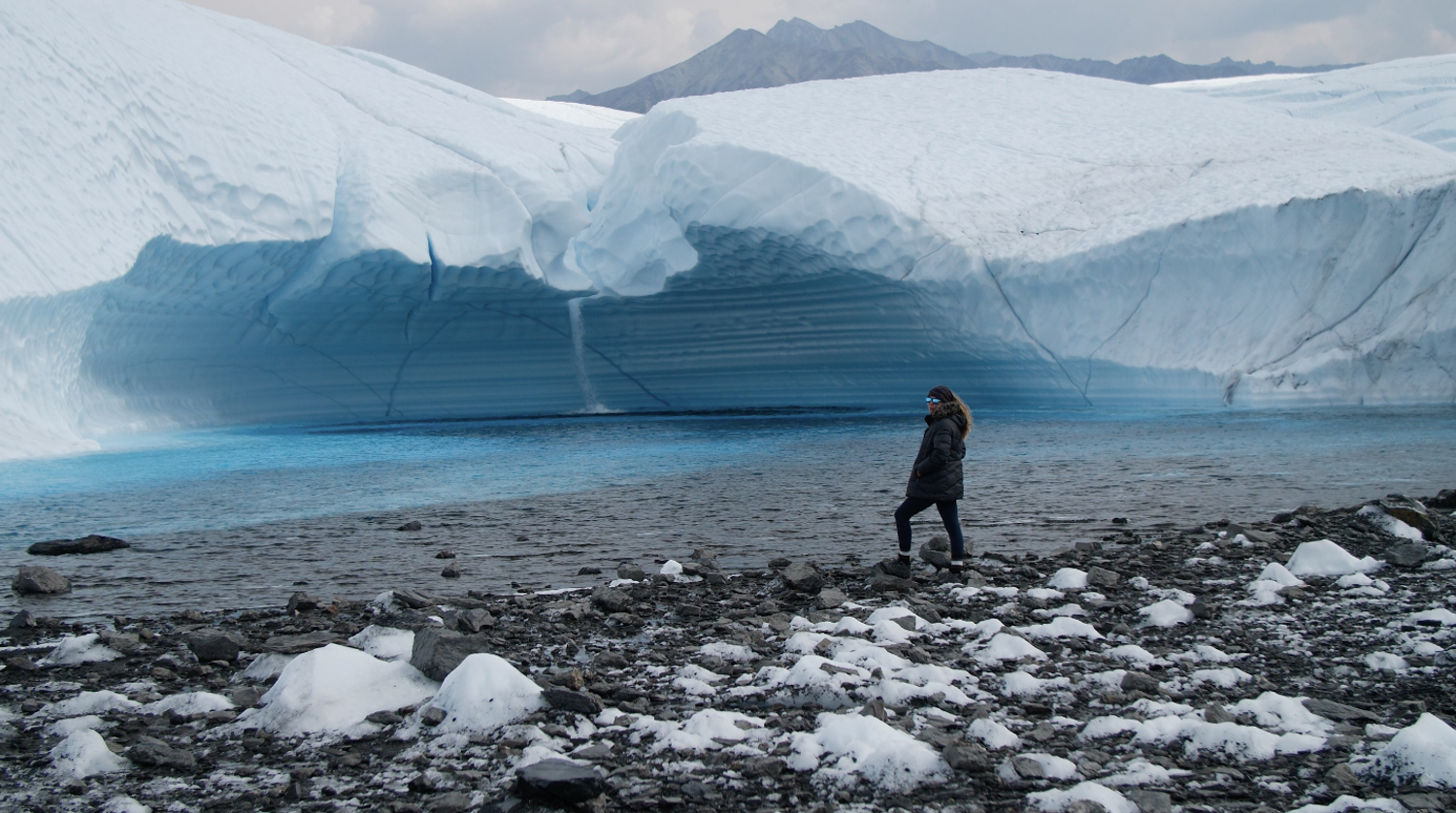 person standing in front of glacier waterfall