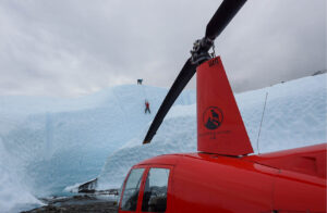 view of helicopter propeller with ice climbers in the distance